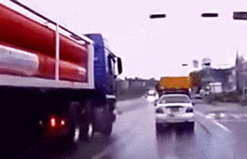 A small car drifts into the next lane in front of a large semi-truck, and is pushed along the road
