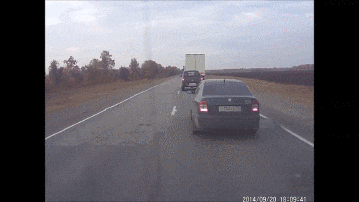 The first-person point of view of a car passing traffic, forced to swerve to the shoulder on the left side of the road to avoid a head-on collision with a semi truck