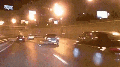 A speeding car swerves in and out of traffic on a busy freeway at night