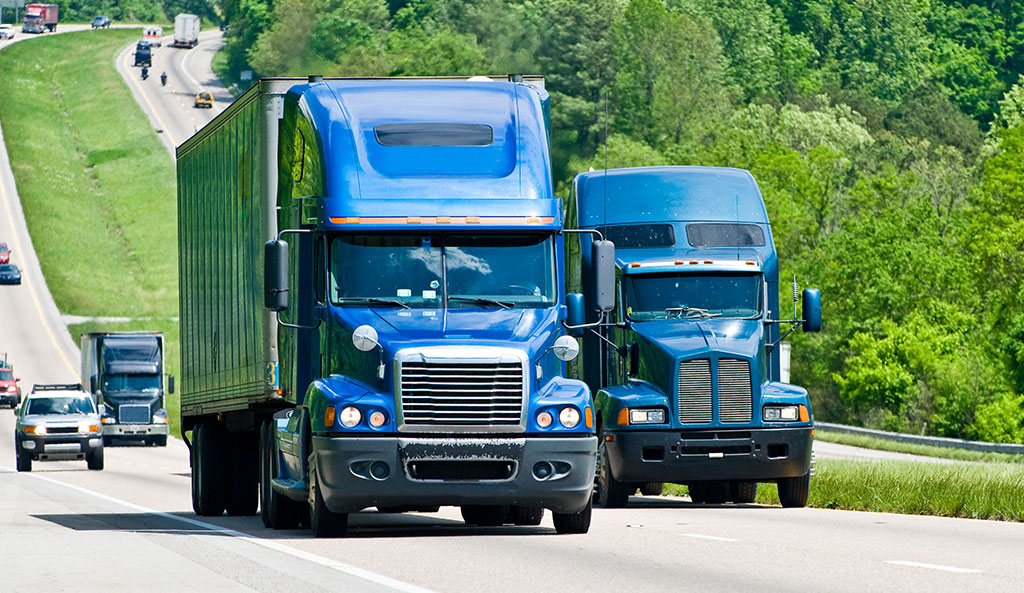 Two blue Semi trucks driving on highway