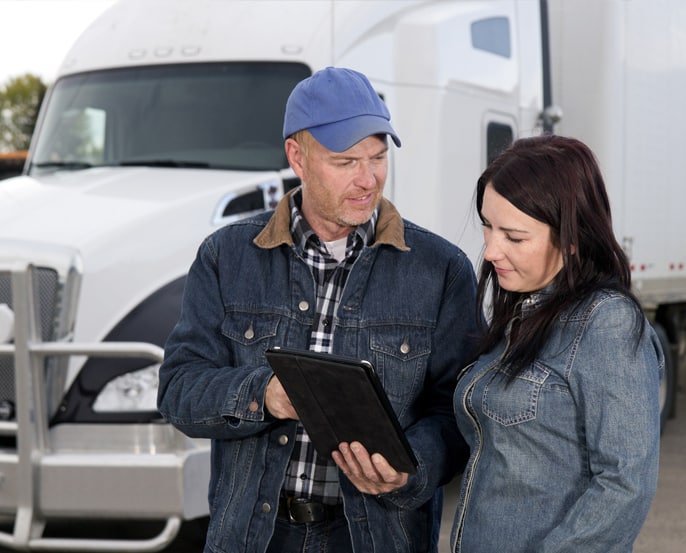 Male and female truck drivers discussing information on an iPad