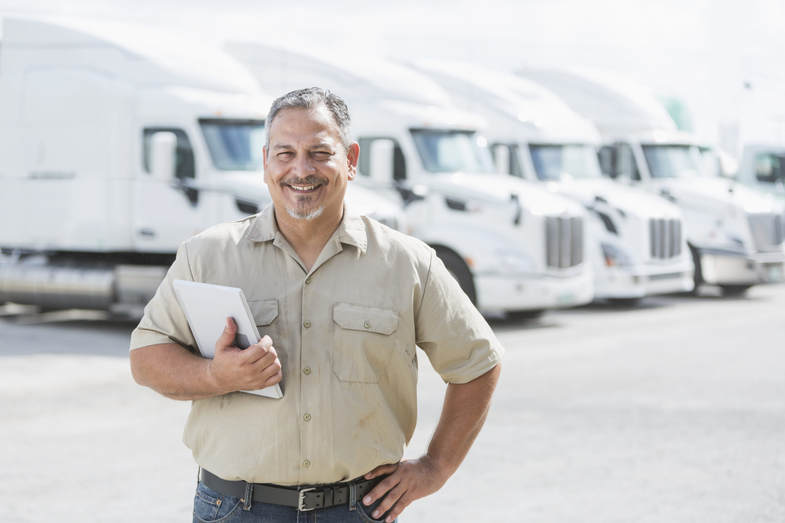 Hispanic man standing in front of semi-trucks